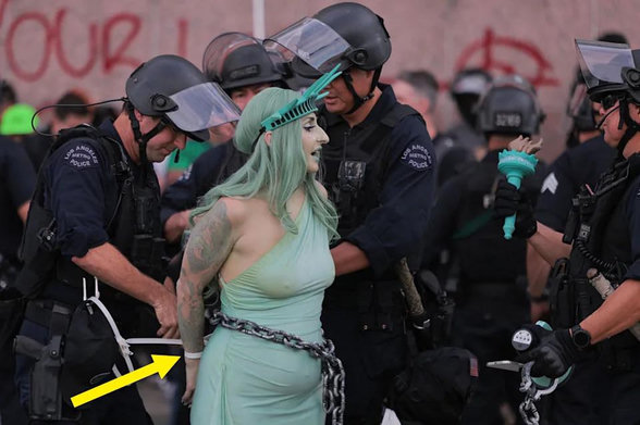 A closer shot of the woman dressed as the Statue of Liberty getting arrested.