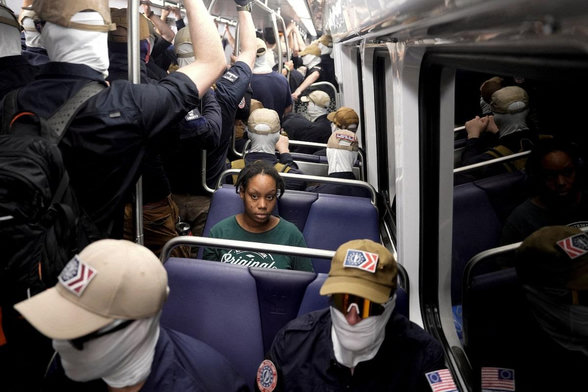 Photo by Cheney Orr taken this morning (July 4, 2026) on the DC metro. Group of masked white supremacists are looming on the subway, as one lone Black woman sits uncomfortably in a seat.
