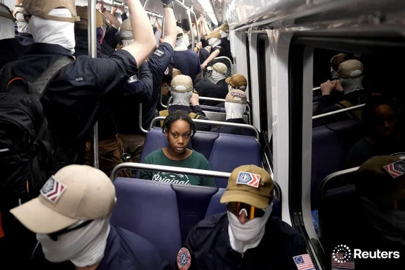 A subway car full of Patriot Front Nazis with one black woman looking at the camera