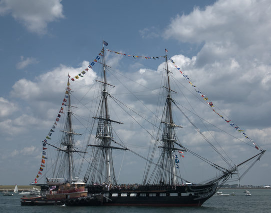 The USS Constitution heading out of Boston Harbor for its 4 July turnaround cruise, attended by the tug Harold A. Reinauer II