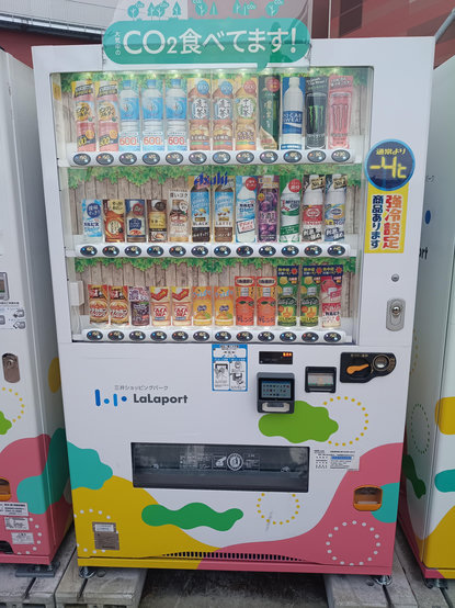 A drinks vending machine with a banner declaring 大気中のCO²食べてます! ("I am eating atmospheric CO²!").