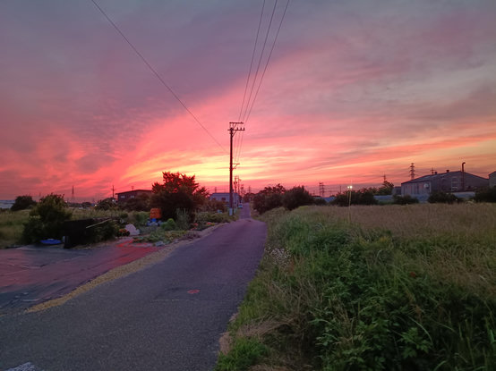 Sparse overcast lit up in fiery pink and red as the sun sets behind.