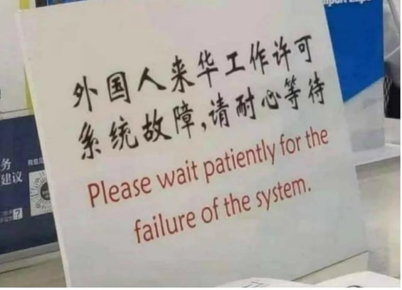 A sign in an East Asian language. It is accompanied by an English translation which reads, “Please wait patiently for the failure of the system.”