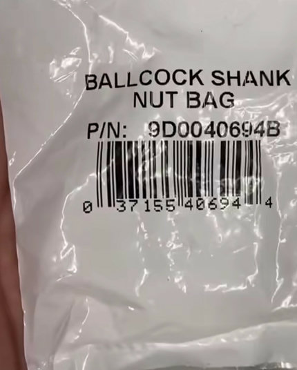 A plastic bag labeled “ballcock shank nut bag”.

It has a part number of 9D0040694B and a UPC of 037155406944.

This UPC, according to a cursory web search, is indeed a ballcock shank nut, intended for use in repairing leaky toilets.