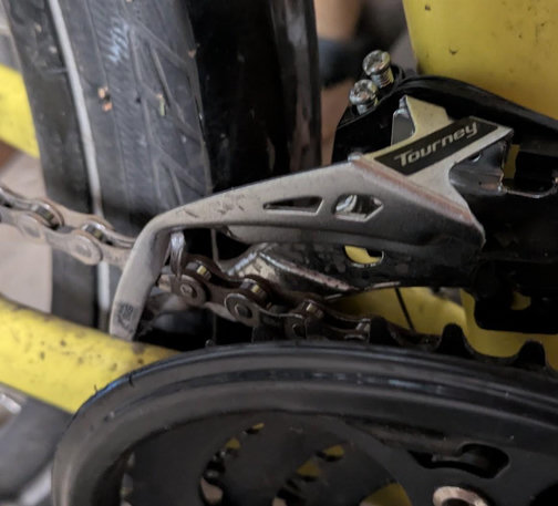 Bike derailuer close up, it is roughly bent where the chain contacts it.  There's a little piece of metal that appears out of place.