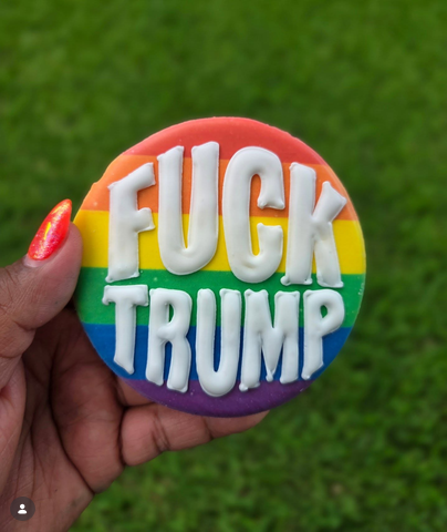 From Cookies by Chrysta in Dallas, Texas, a picture of a cookie with "FUCK TRUMP" in white block letters over an expertly iced Pride flag background.