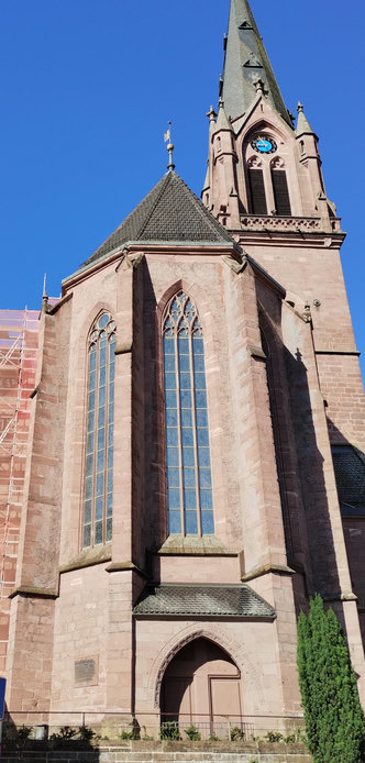 Kirchturm und Chor einer Kirche mit gotischen Maßwerkfenstern.