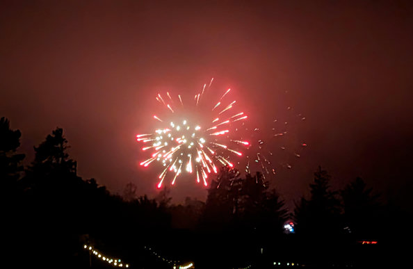 Red and white fireworks light up the sky down the hill from our house.