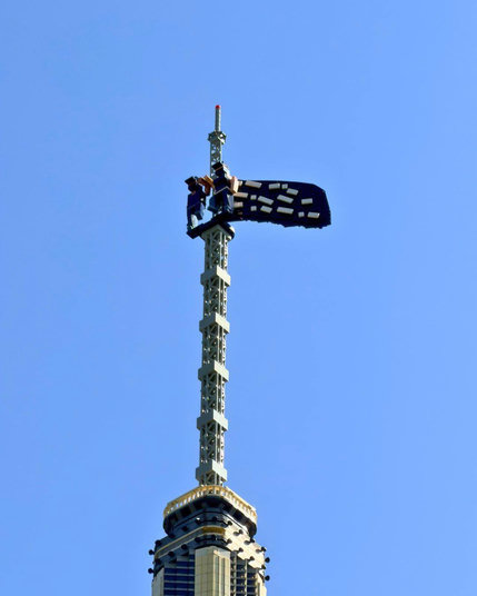 Two tiny figures and a black flag added to the spire of the Empire State Building Lego model