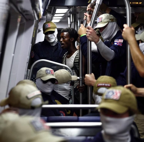 Black man on a bus surrounded by white (fascist) masked men.