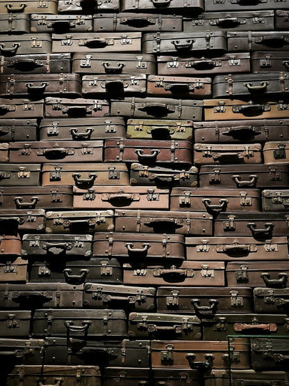 Eine Ganze Wand bis an die die Decker gestapelte alte Koffer