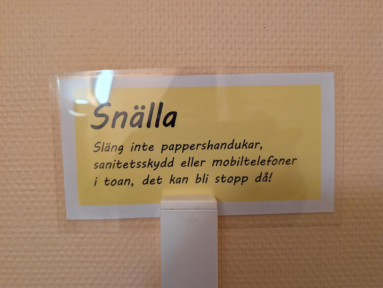 En skylt från en herrtoa där dom ber att inte spola ner mobilen 
