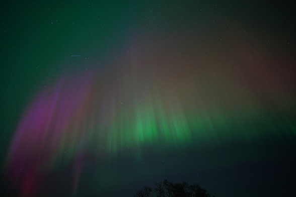 An arc made of vertical columns starting green at the bottom, transitioning to orange and then red then purple at the top, with green in the background of the sky.