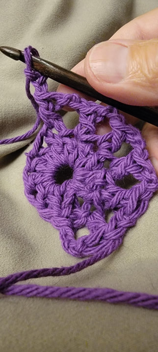 Beginnings of a crochet in the round, with purple cotton yarn.