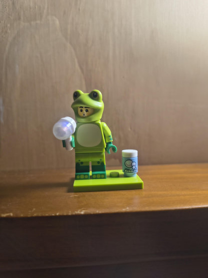 A Lego minifig. They're wearing a frog suit and blowing bubbles y'all how cute is that 🥹