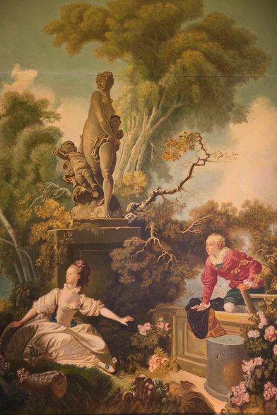An 18th-century pastoral painting of an idealized classical bucolic garden setting in which two richly clad nobles (a male-female pairing) are playfully flirting below a statue of Venus.