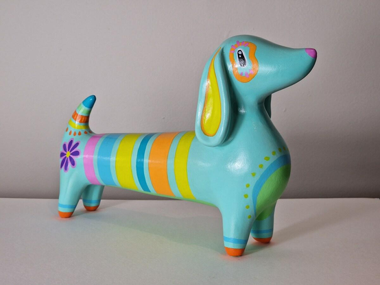 Large ornament of a mint green sausage dog covered in coloureful stripes, patterns, and flowers