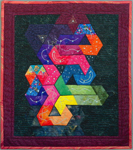 "Anitra's Dance". Rectangular wall quilt made of tiled triangles. They are arranged to fill a spacj with a meandering line. There are triangular rhinestones and there is wavy metallic embroidery.