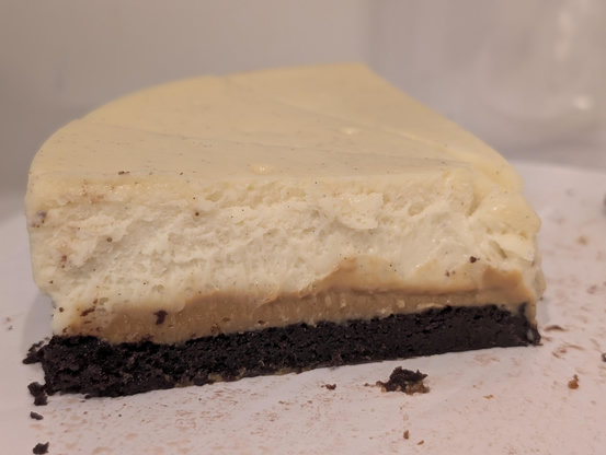 Photo of a few slices of cheesecake with a brownie crust and a caramel colored filling of a stiff dulce de leche