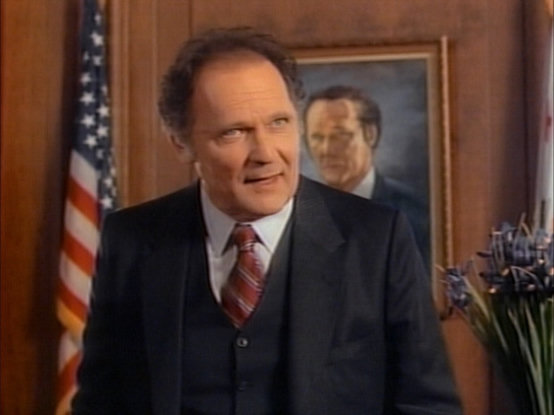 John Vernon standing in front of a painting of John Vernon