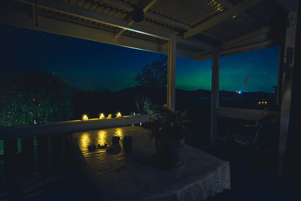 A photograph taken from a veranda, with the camera facing north. The Swedish west coast on a late summer evening. You can just make out the Northern Lights in the sky.