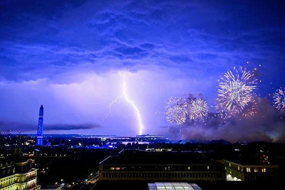 Pic of July 4 fireworks in Wash DC with lightning bolt in the background and thick clouds lit up from below