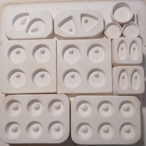kiln shelf with a bunch of empty molds. here is all the shapes of pendants they are making:
2 teardrops
2 fat triangles
1 large circle without a hole (all the other ones have holes for cord)
2 small circle without holes
8 large (about 2 inches across) circles (we're back to holes all the rest have holes)
4 ovals
12 small weighted donuts (i don't know what to call these but they are rounded on the bottom when the others are flat, so its less obvious in a finished piece which side is the top, and the hole is offset in a way that makes them bottom heavy)