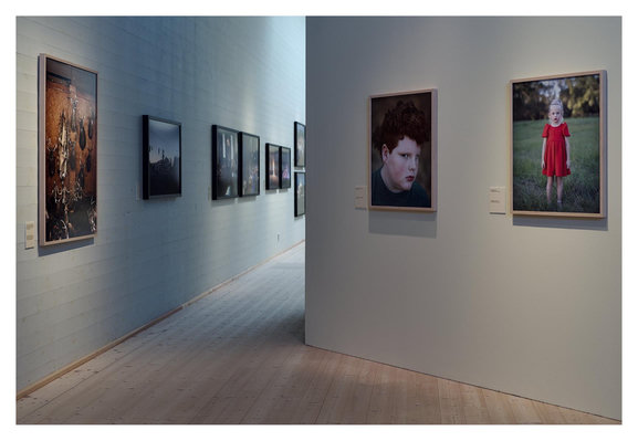 En liggande bild pÄ en fotoutstÀllning pÄ ett museum. TvÄ vÀggar med bilder.