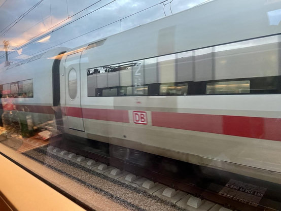 Blick durchs Zugfenster auf einen vorbeifahrenden ICE