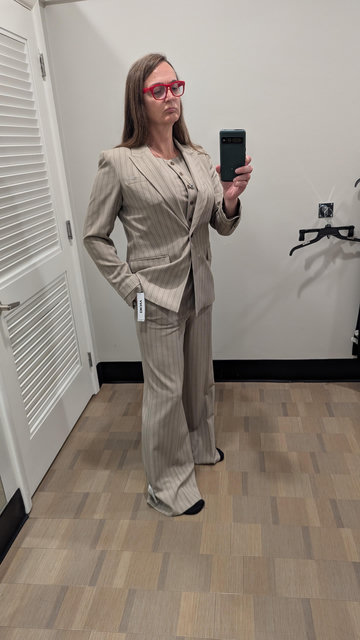 photo of Coleen in a cream pinstripe suit with matching vest and her jacket buttoned with her name in her pants pocket