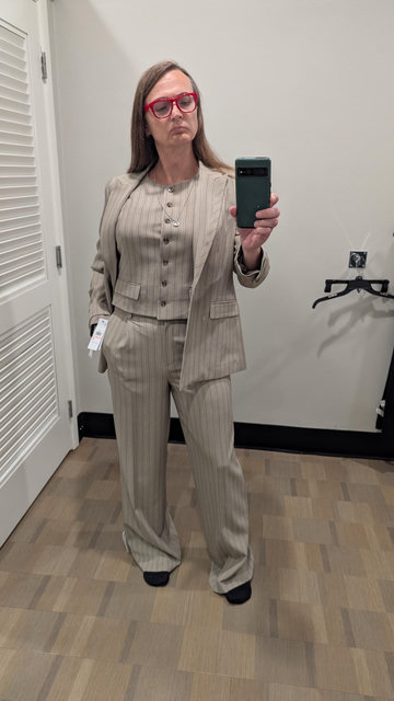 photo of Coleen in a cream pinstripe suit with matching vest and her jacket open with her name in her pants pocket
