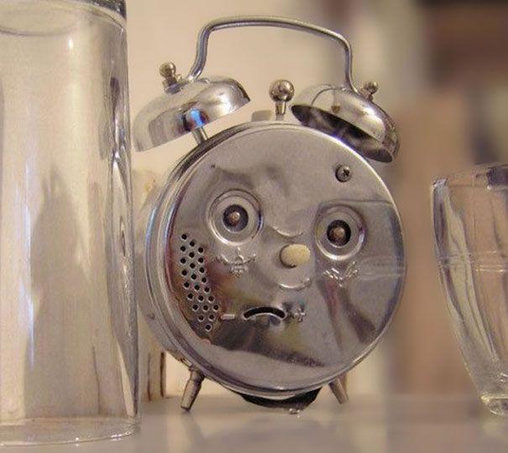 The back of a vintage wind-up alarm clock that looks like an upset cartoon character.
