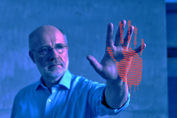 "Terra X Harald Lesch ... und wie KI uns überwacht": Montage, blau verfremdet: Harald Lesch steht unscharf im Hintergrund, trägt ein Hemd und hat seine Hand nach vorne gestreckt. Die Handinnenfläche ist scharf und Richtung Kamera geöffnet. Über der Handfläche ist eine Grafik in Gestalt einer Hand mit roten Einsen und Nullen gelegt.