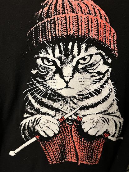 Illustration of an angry cat, wearing a beanie, and knitting.