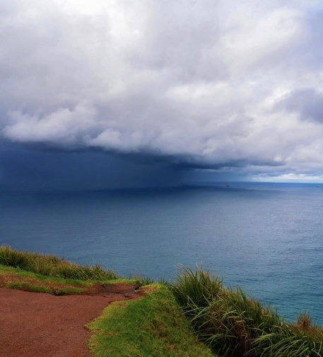 Wollongong coast just after sunrise on a rainy morning, low thick cloud and calm sea
I'm standing on the edge of a small hill, which ends sharply and overlooks calm sea. The soil path is a deep rust colour which contrasts with the blue sea and thick white cloud.