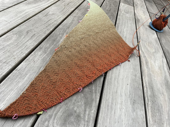 Das unfertige Tuch liegt auf grauen Terrassendielen, daneben das teils aufgebrauchte Knäuel.