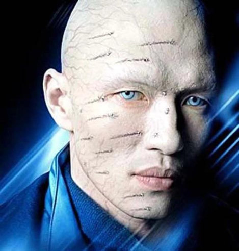 A close-up portrait of a bald, pale Asian man with striking blue eyes. Their face and head are covered in subtle, parallel rows of embedded diamonds. They are looking directly forward against a dark background with dramatic blue light streaks.