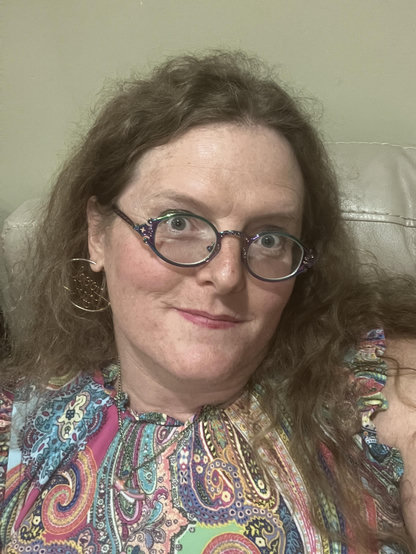 miriam, four years after egg crack, in a paisley dress and "good girl" hoop earrings. her features are sharper and cleaner, hair frizzy but cared for. she looks tired but still put together.