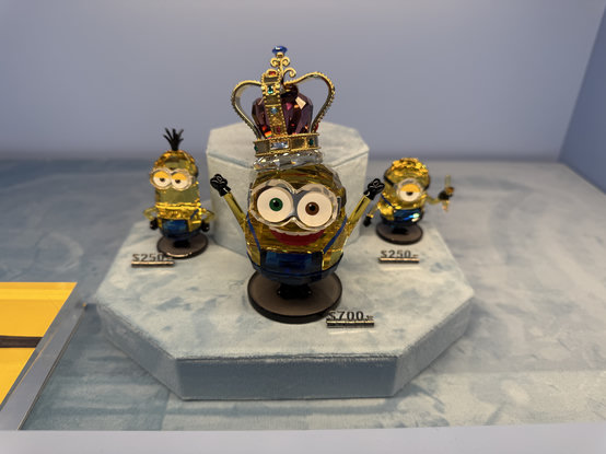 Three glass minion figurines at a Swarovski store, ranging from $250 to $700
