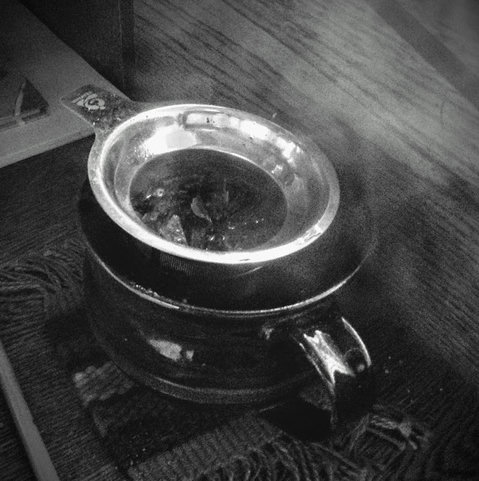 Fresh leaves of, perhaps, dandelion, self-heal, and red willow brewing in a mug made for shonin by an old potter friend.