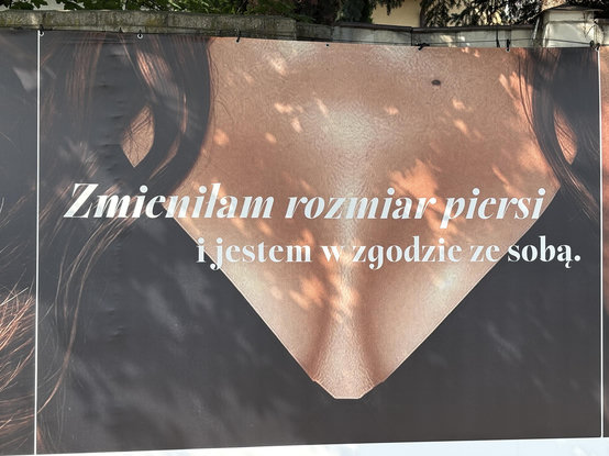 Reklama zachwalająca możliwość zmiany wielkości piersi w formie zbliżenia na opalony biust. Hasło: "Zmieniłam rozmiar biustu i jestem w zgodzie ze sobą"