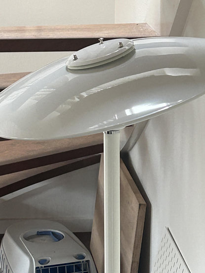 A white floor lamp. The screen has been beaten completly out of shape. The result of a kitten jumping from the nearby stairs (visible in the background) and down on it.